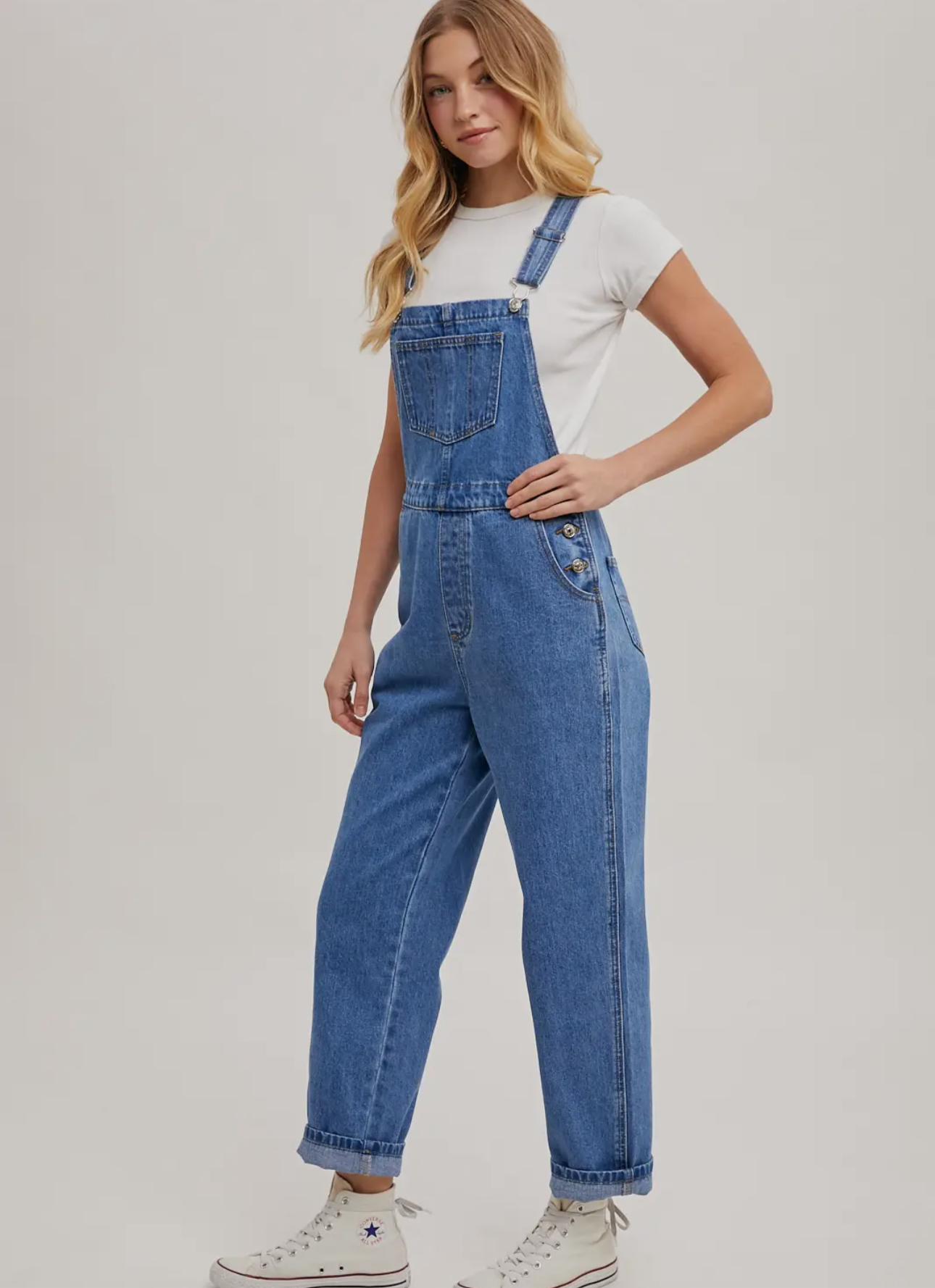 Person wearing blue denim overalls on a plain background